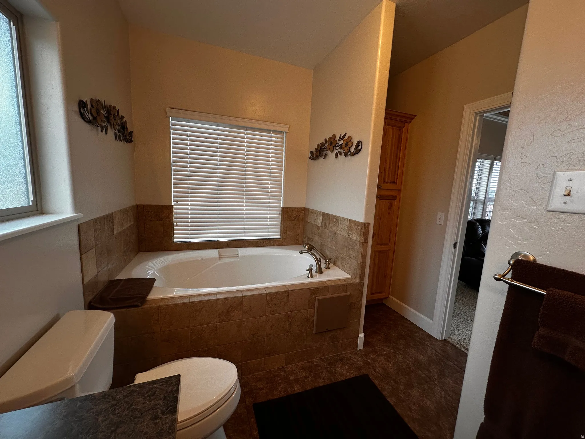Primary 5 piece  bathroom featuring a garden tub, dark tile patterned floors, and a textured wall
