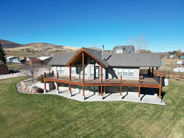 front deck of house featuring a yard, a patio area, a deck with mountain view, and a shingled roof