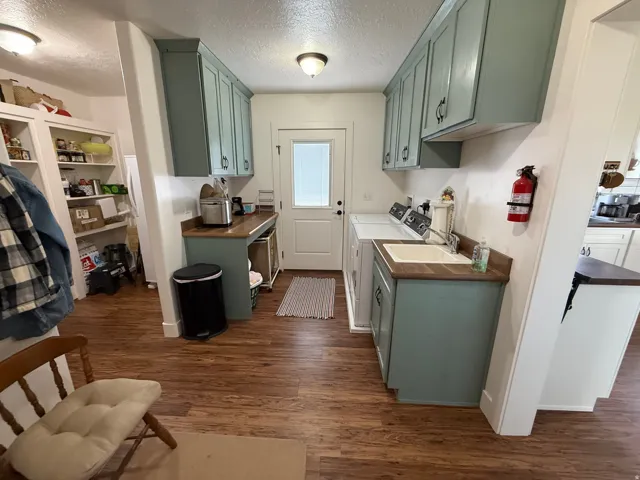 Laundry area featuring a textured ceiling, dark wood-style flooring, washer and clothes dryer, and cabinet space