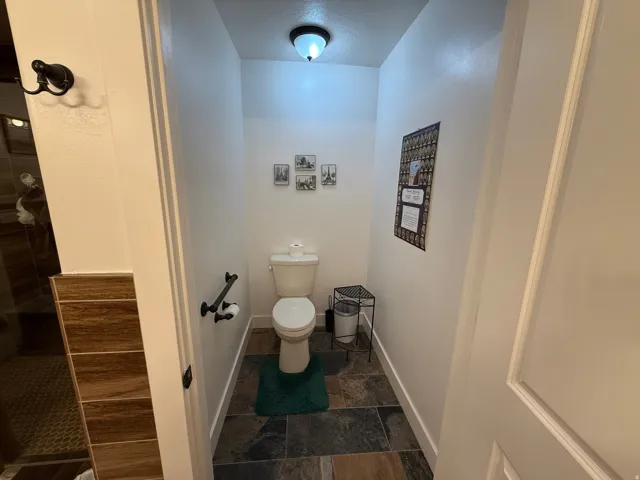 Bathroom featuring dark stone finish floors and a tile shower