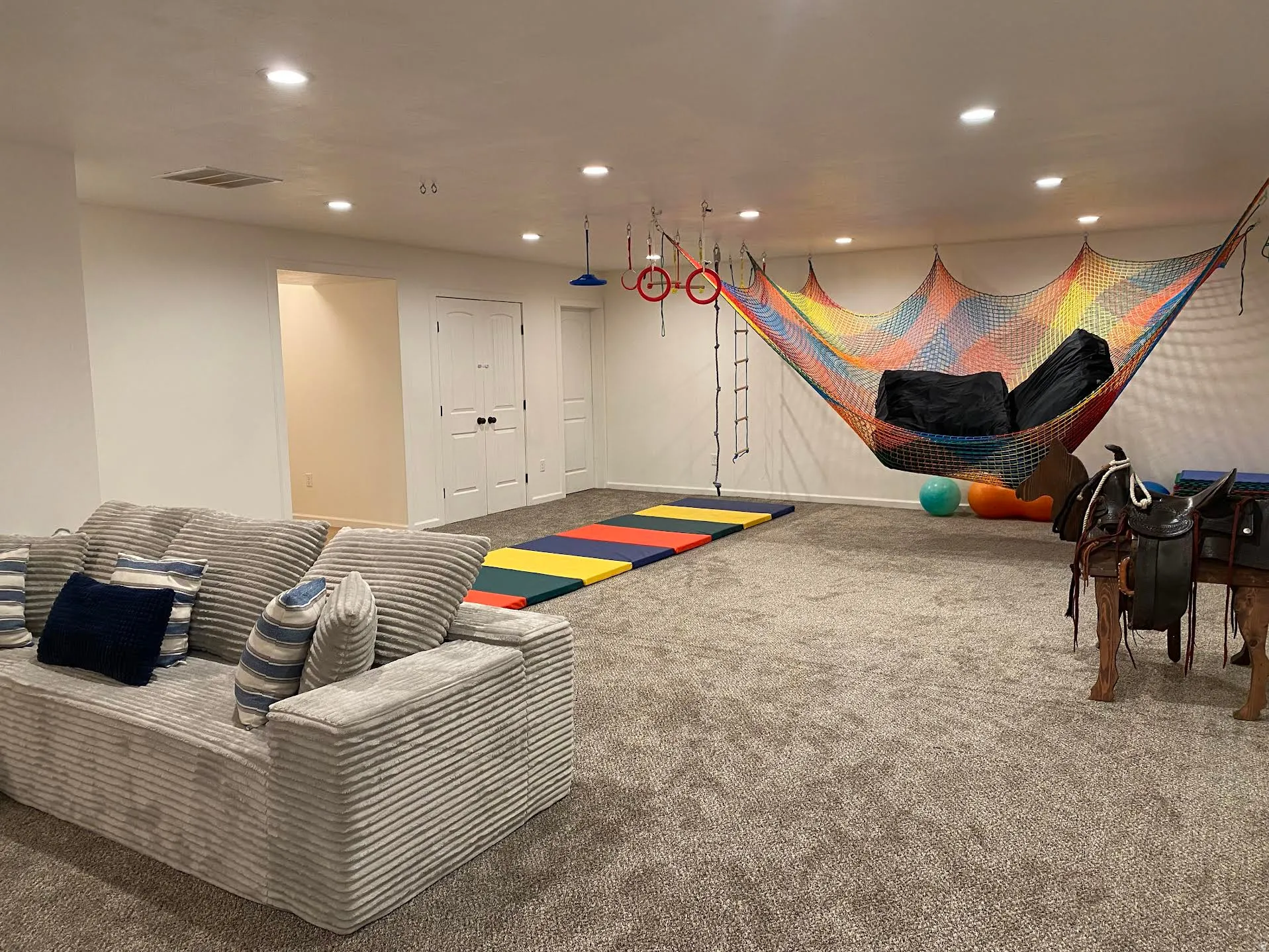 Spacious interior room featuring plush carpeting, recessed lighting, white walls, and white double doors