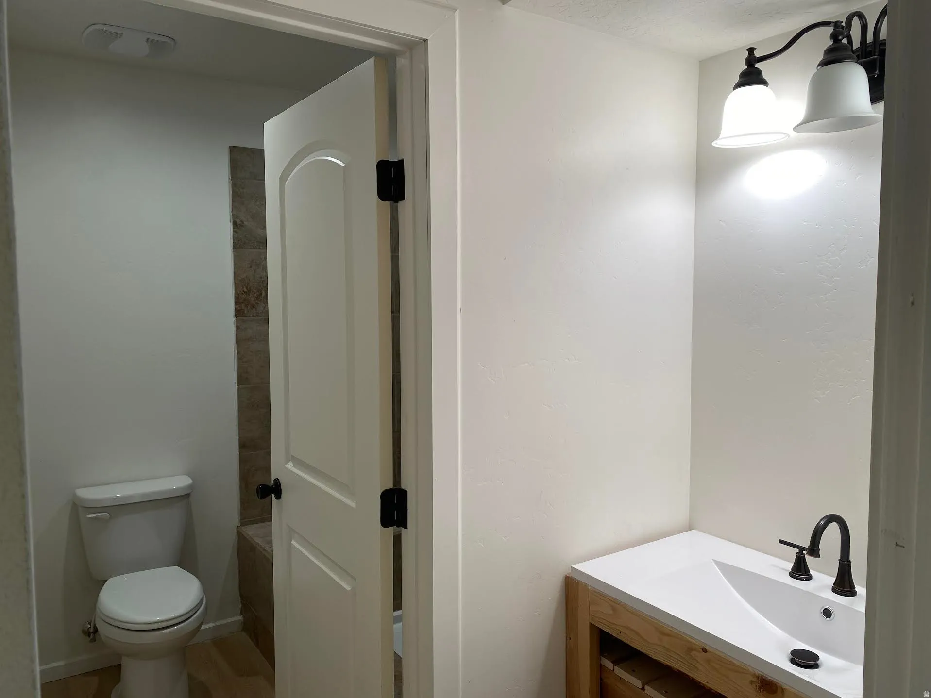 Bathroom featuring a vanity with a white countertop and undermount sink, dark bronze faucet, and a two-light fixture