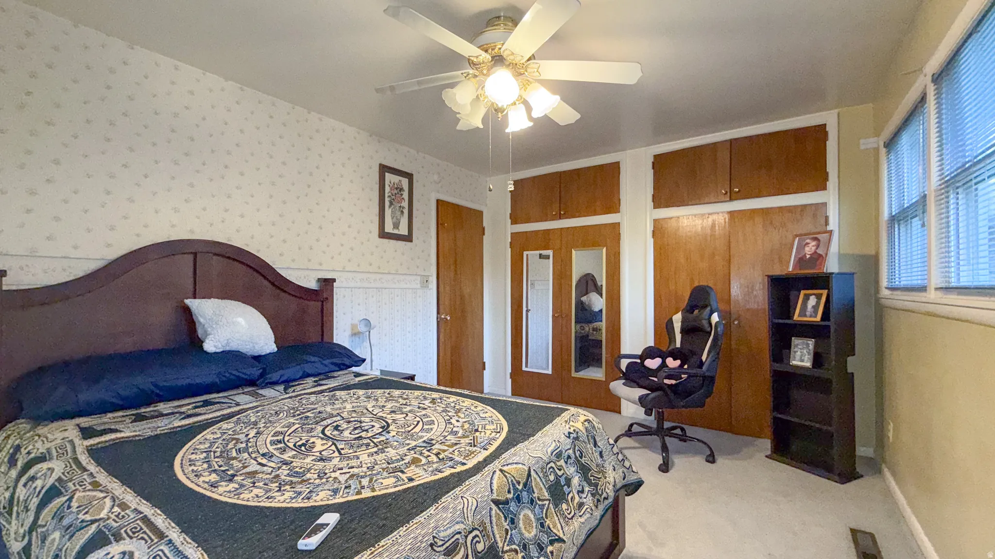 Carpeted bedroom featuring a ceiling fan, wallpapered walls, and an office area