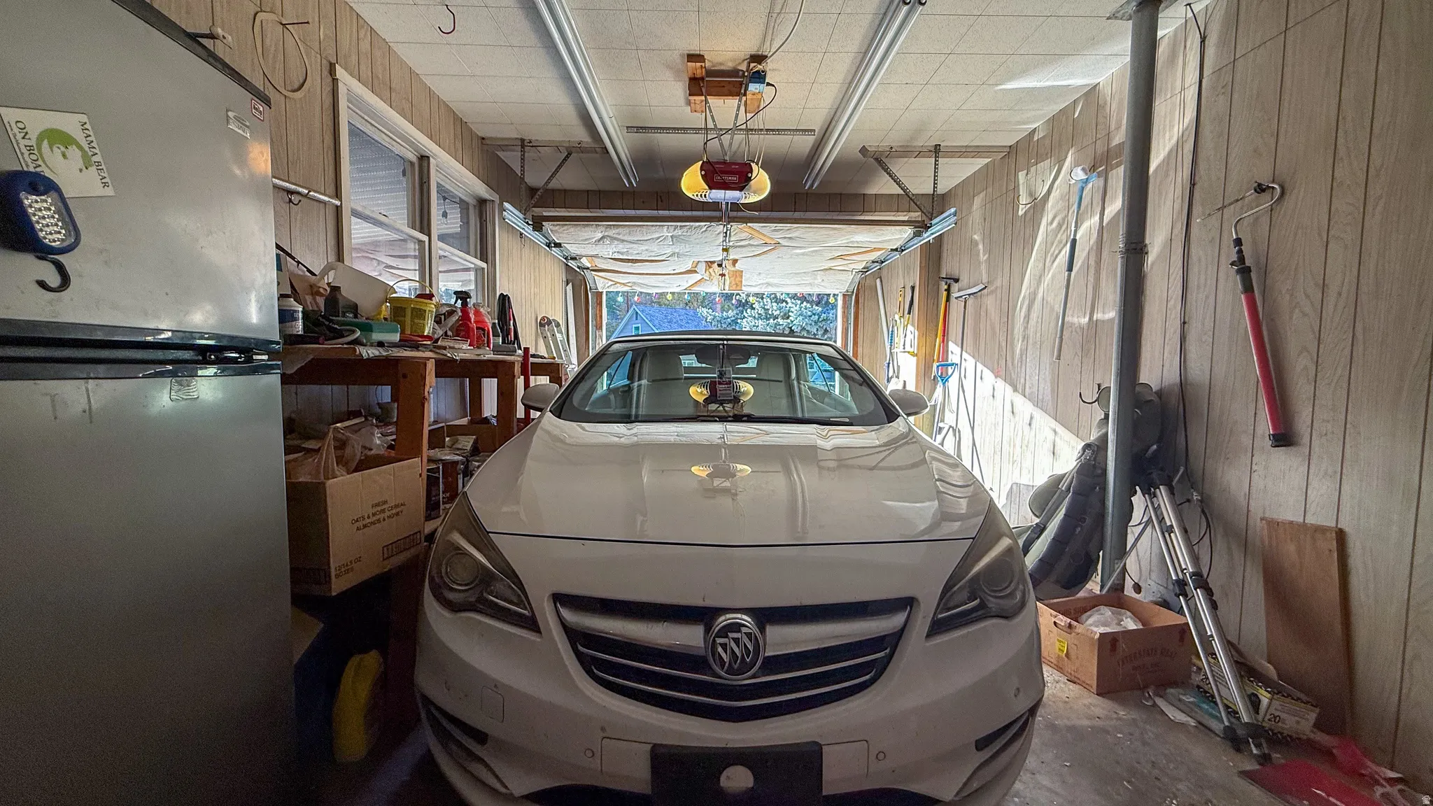 Garage featuring freestanding refrigerator and wooden walls