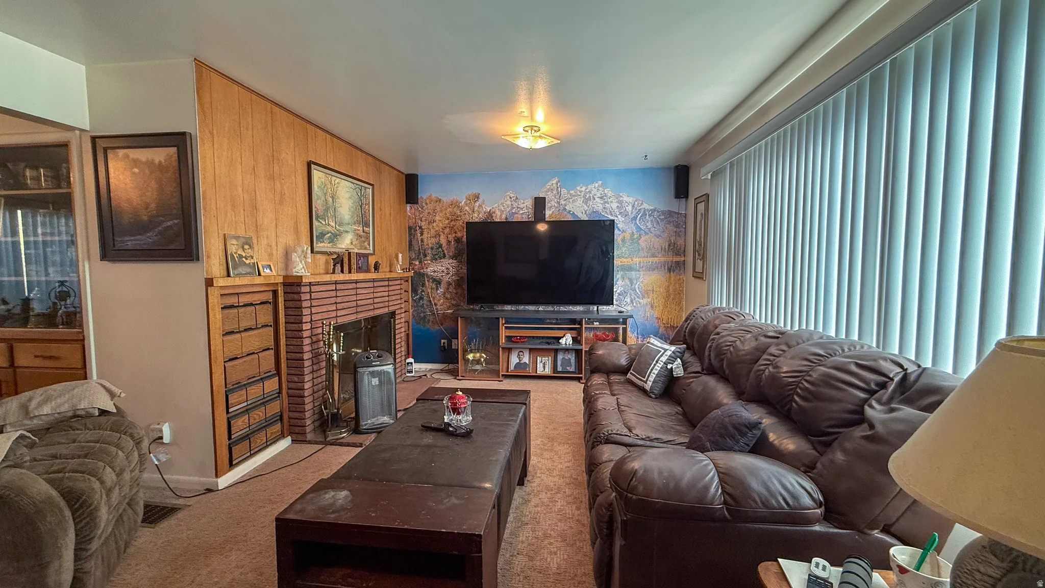 Carpeted living room featuring a brick fireplace and baseboards