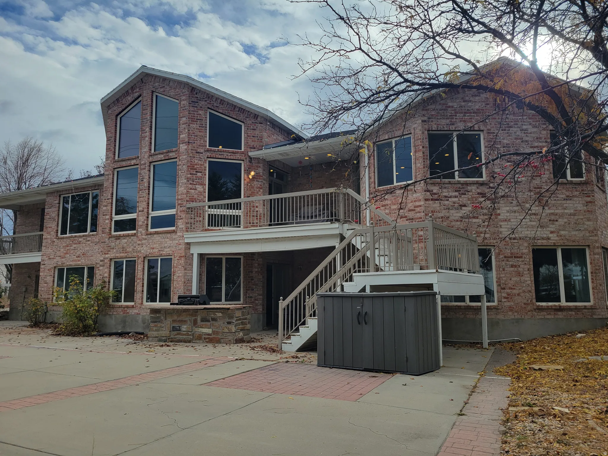Back of house featuring stairway, brick siding, and a patio area