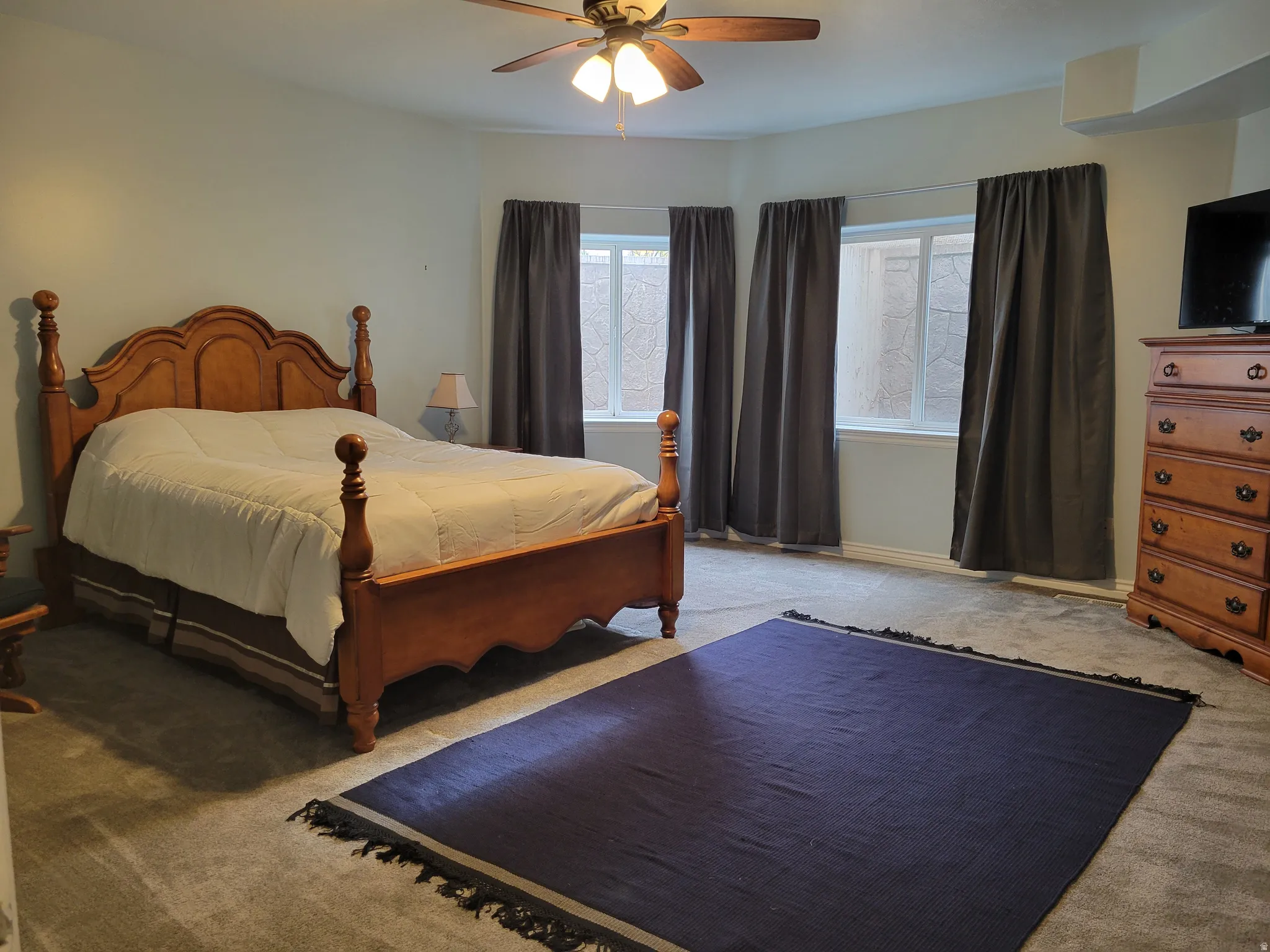 Carpeted bedroom with a ceiling fan and baseboards