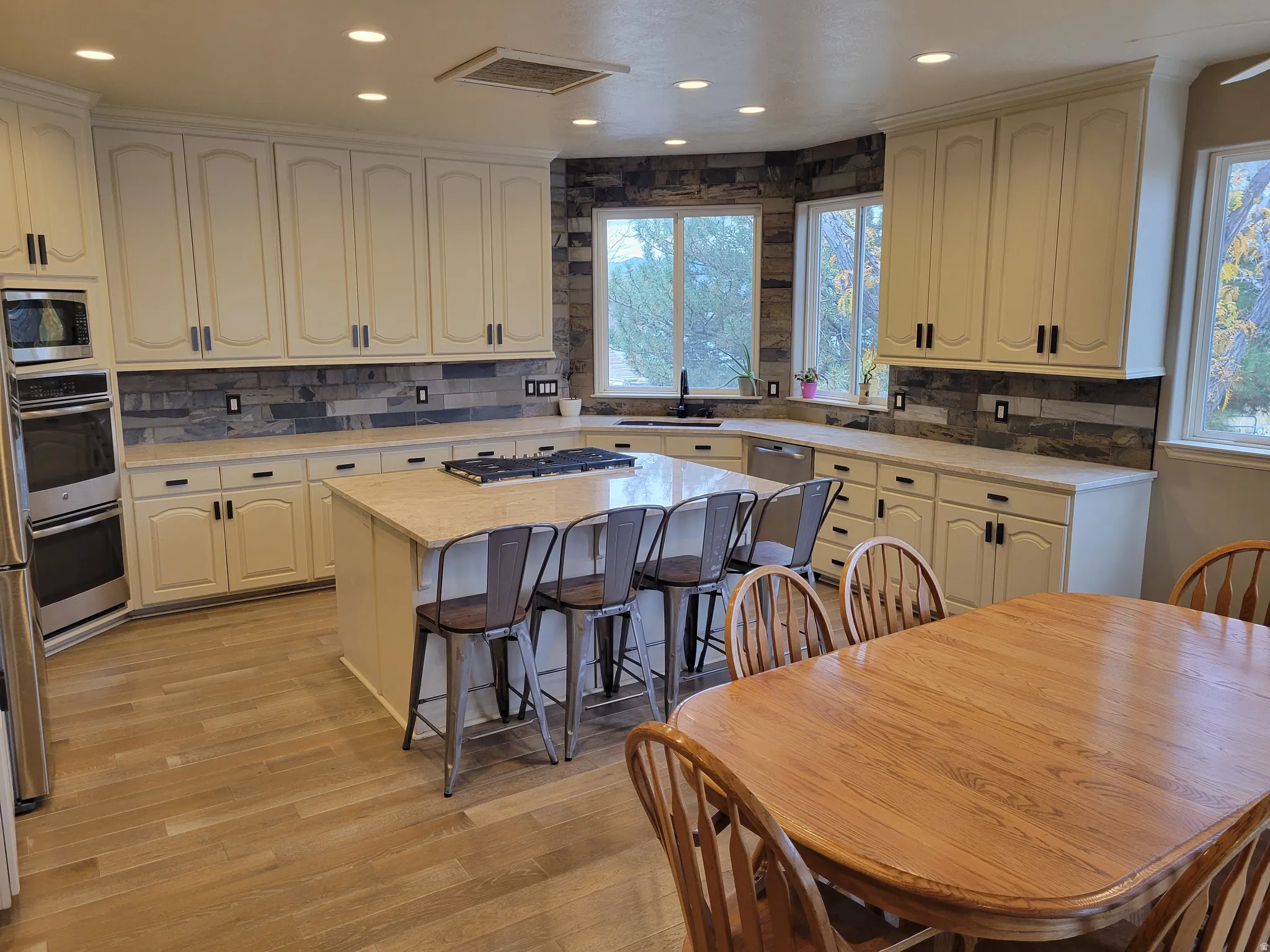 Kitchen with backsplash, plenty of natural light, a kitchen island, light wood-type flooring, and recessed lighting