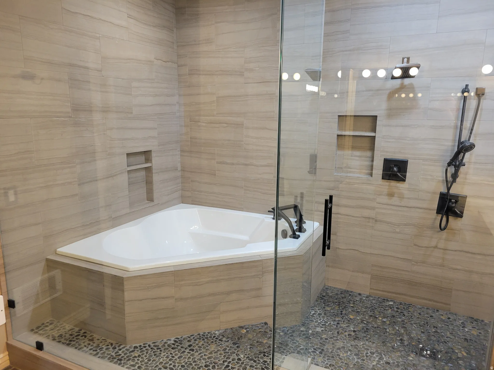 Bathroom with a shower stall, a garden tub, and tile walls