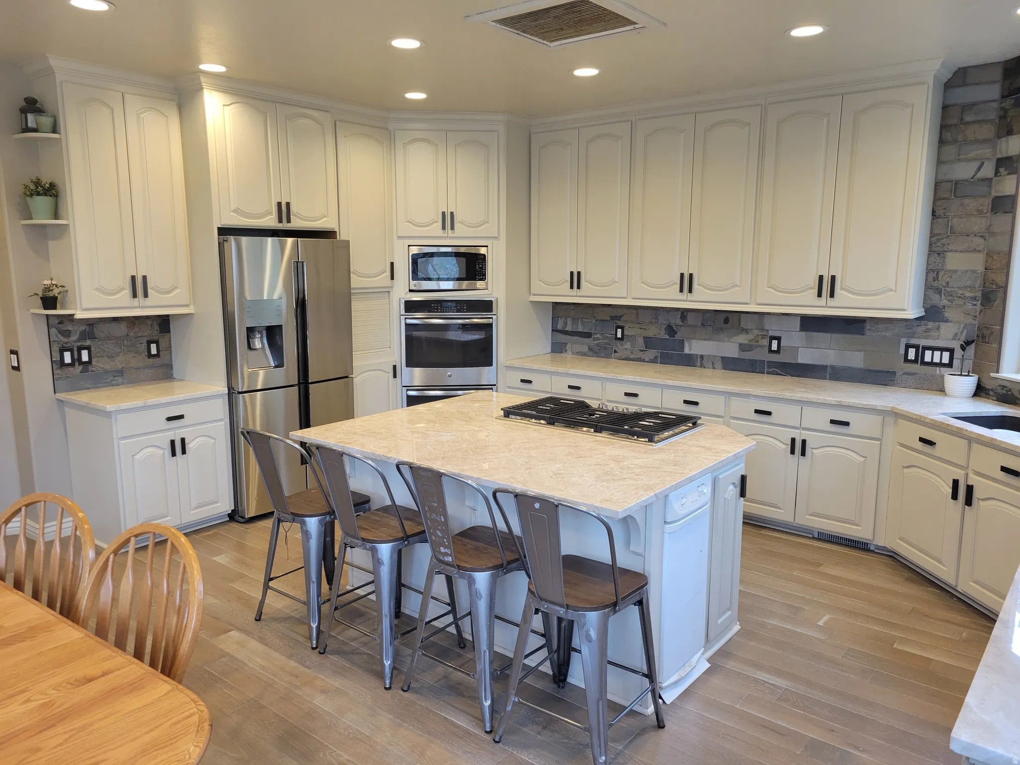 Kitchen with recessed lighting, decorative backsplash, stainless steel appliances, a kitchen bar, and a kitchen island