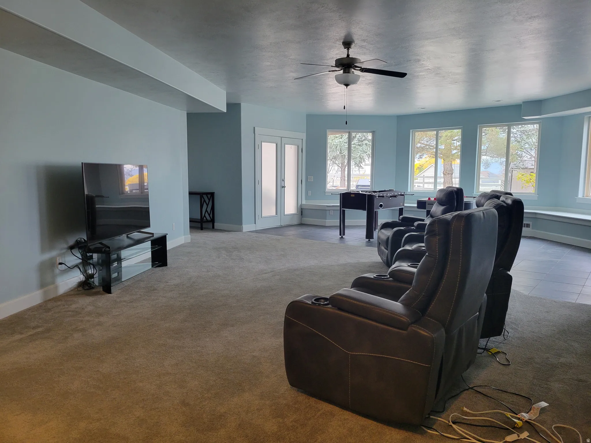 Carpeted living area with french doors and ceiling fan