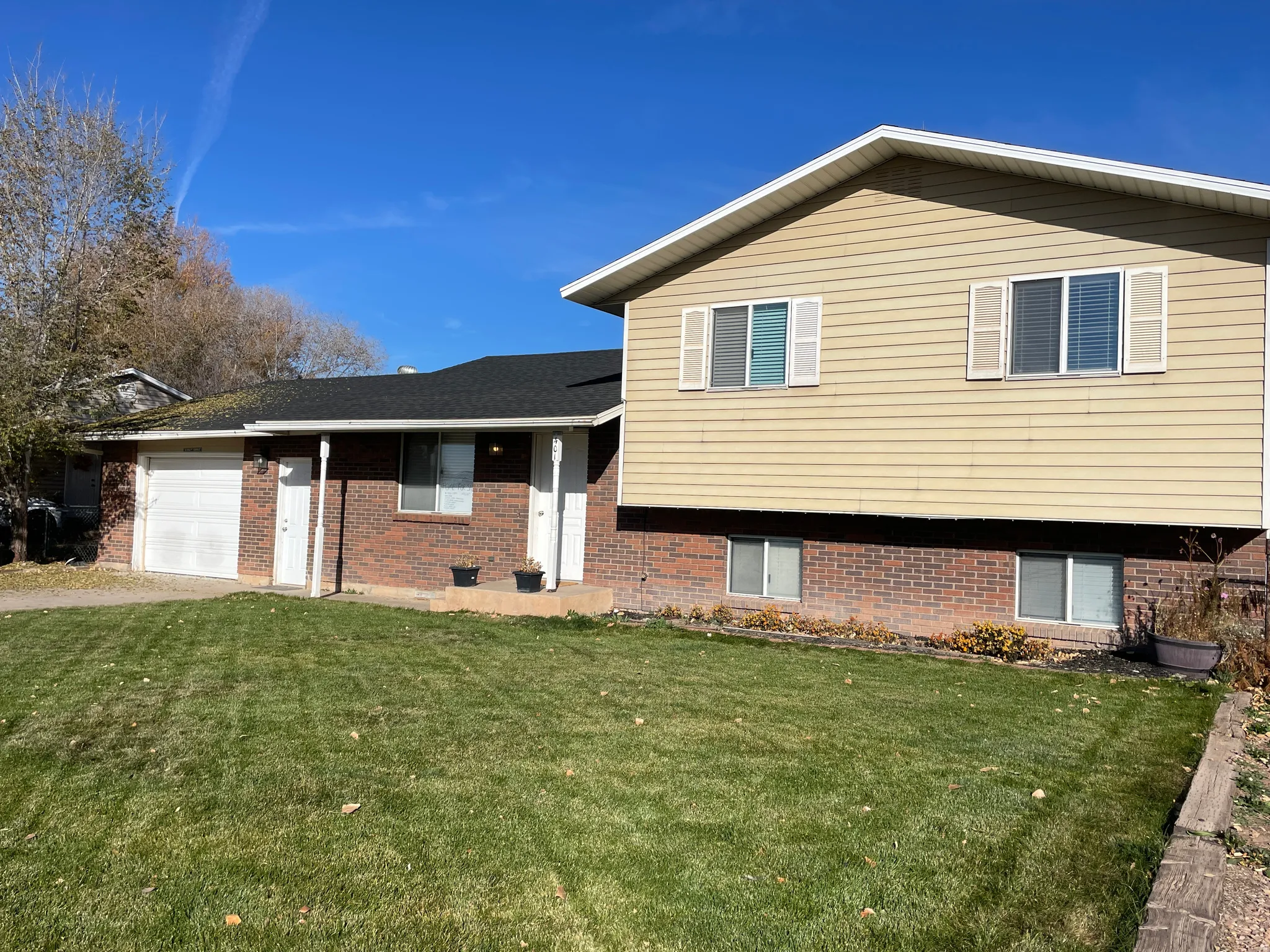 Split level home with a front lawn, brick siding, an attached garage, and driveway