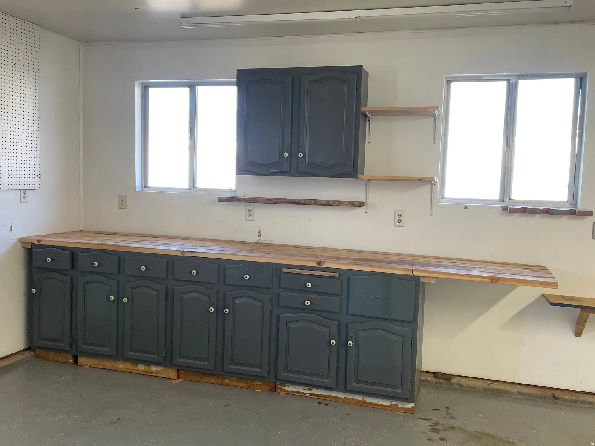 Kitchen featuring concrete floors, butcher block counters, open shelves, and blue cabinets