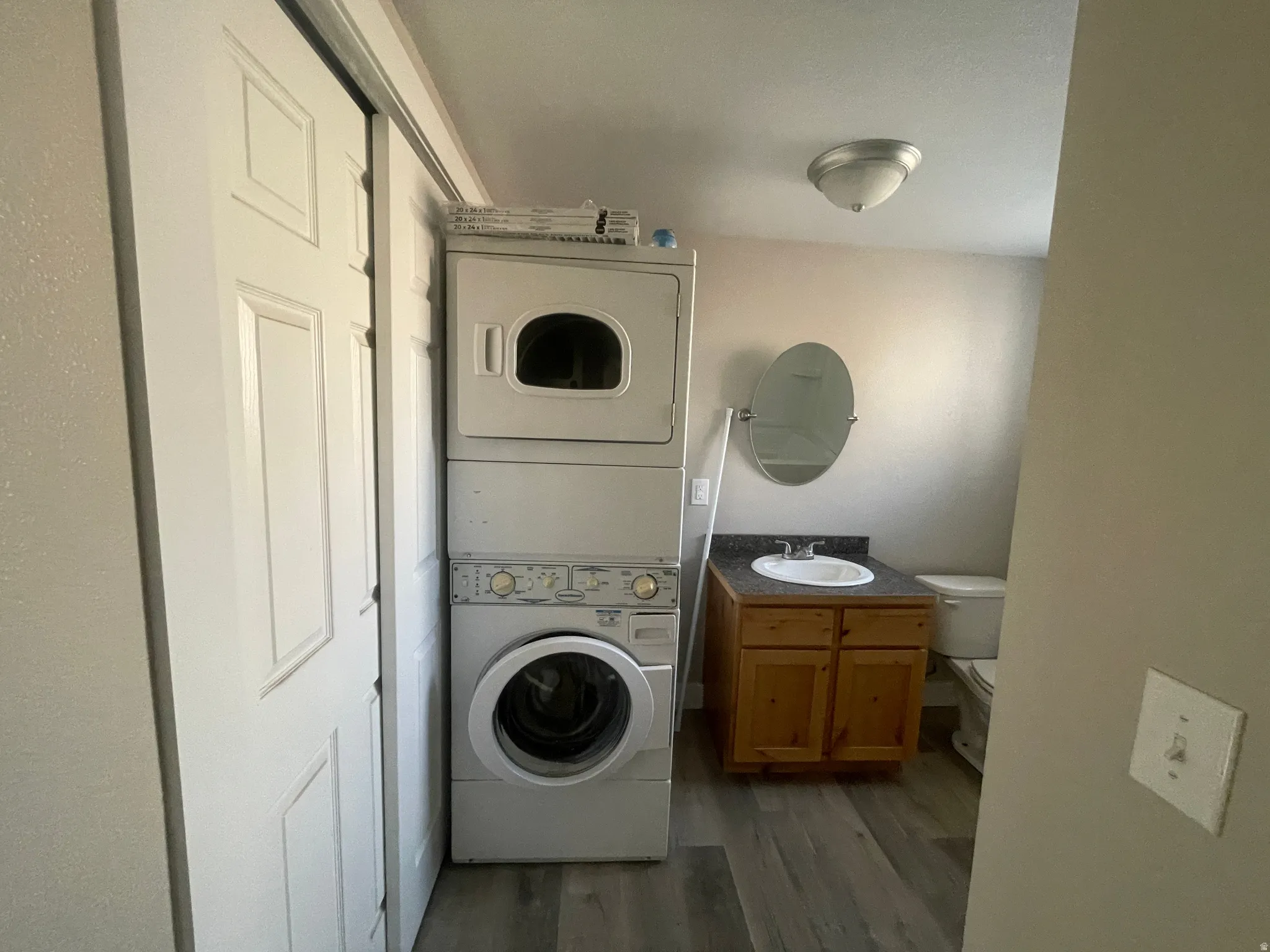 Laundry area featuring stacked washer / dryer and dark wood-type flooring