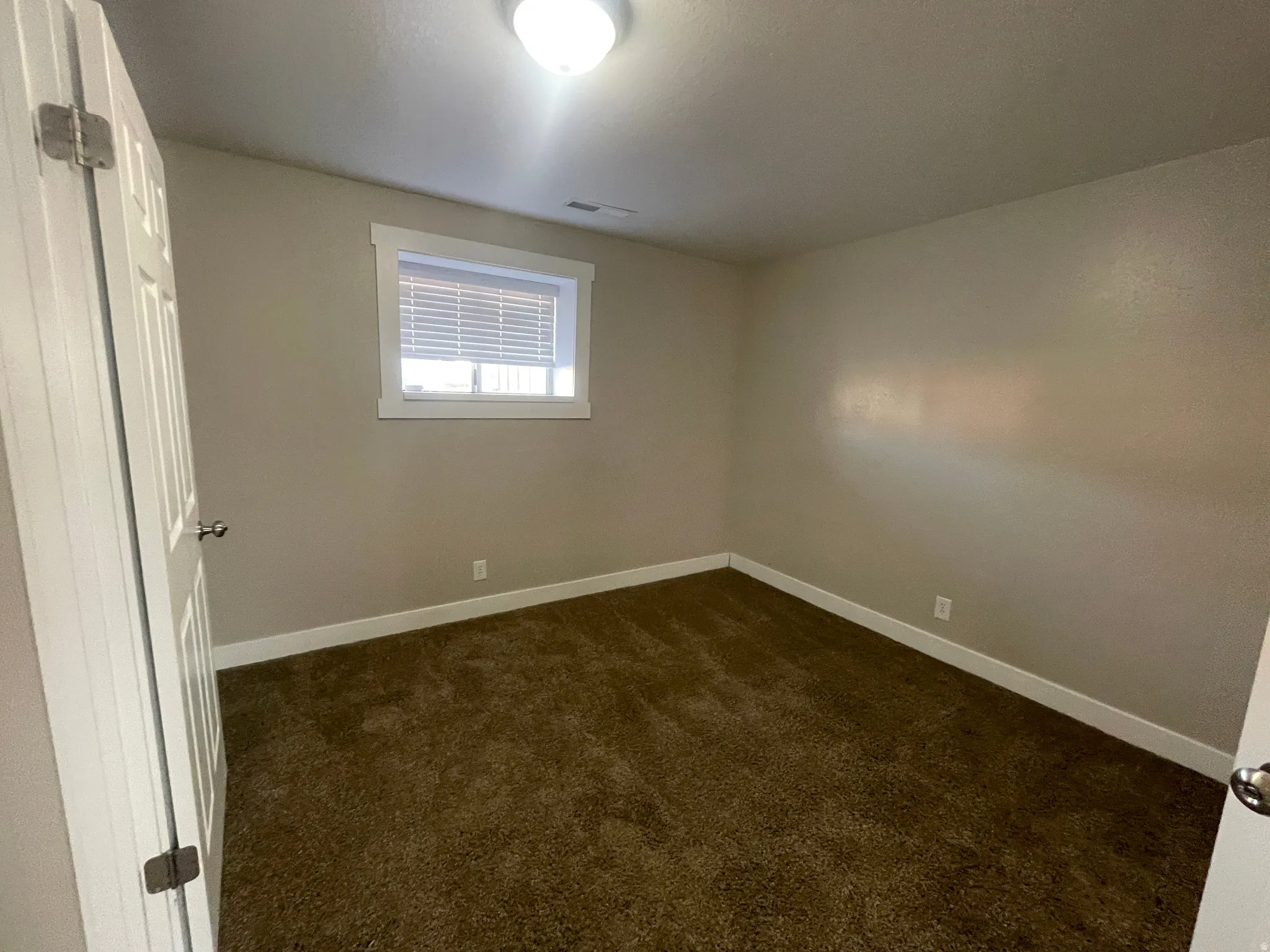 Empty room featuring dark carpet and baseboards