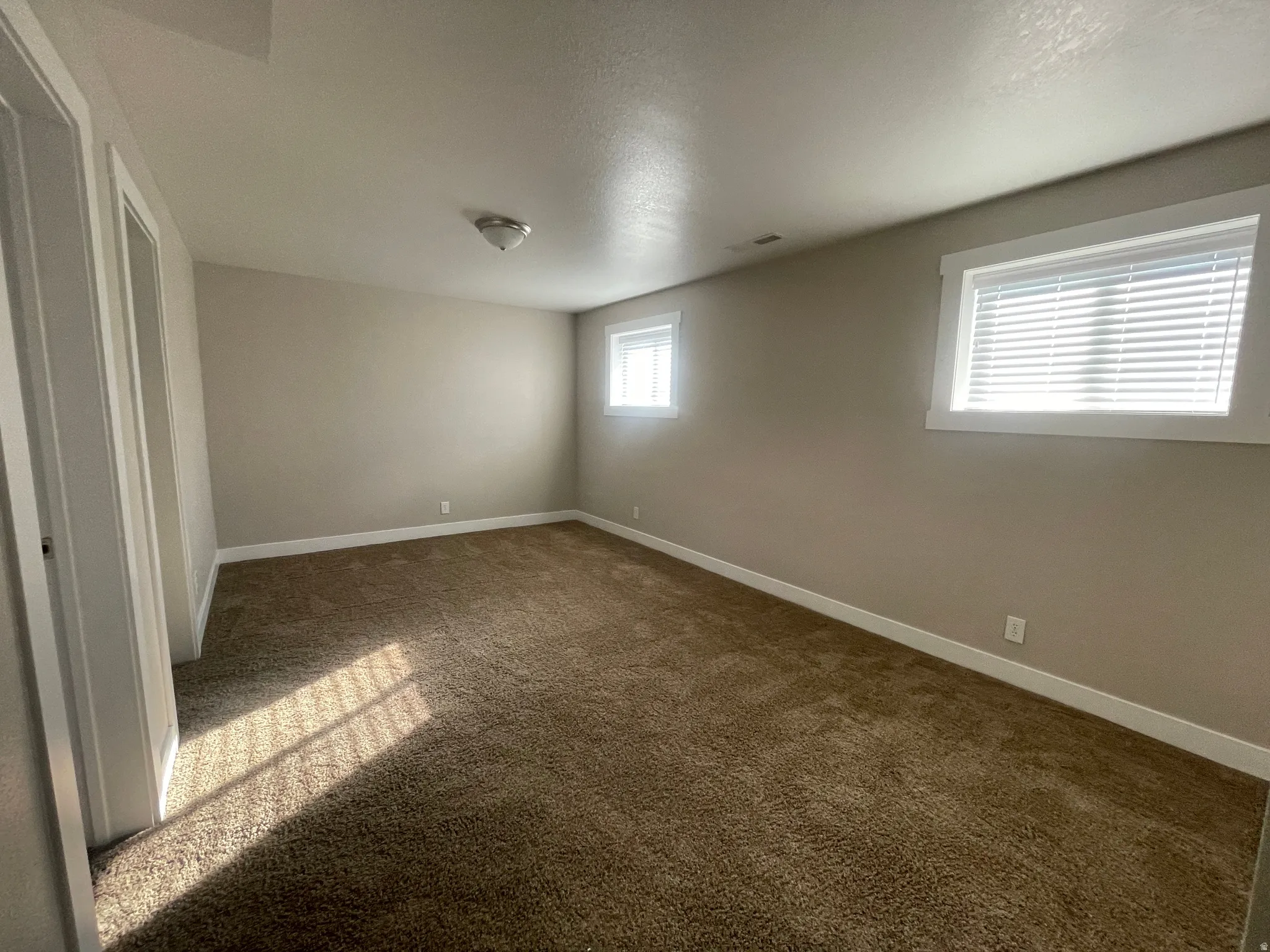 Unfurnished bedroom featuring dark colored carpet and a textured ceiling