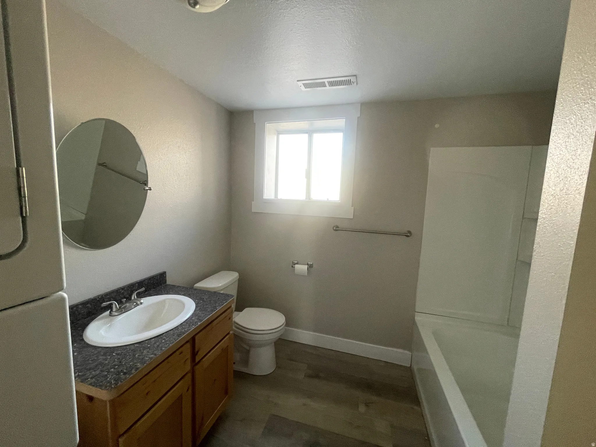 Bathroom featuring vanity, dark wood-style flooring, a textured ceiling, and tub / shower combination