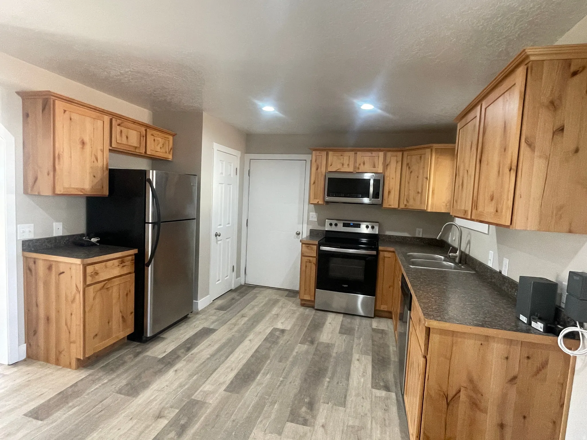 Kitchen featuring dark countertops, light wood-type flooring, stainless steel appliances, and a textured ceiling