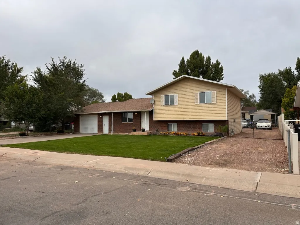 Split level home featuring brick siding, a front yard, and concrete driveway