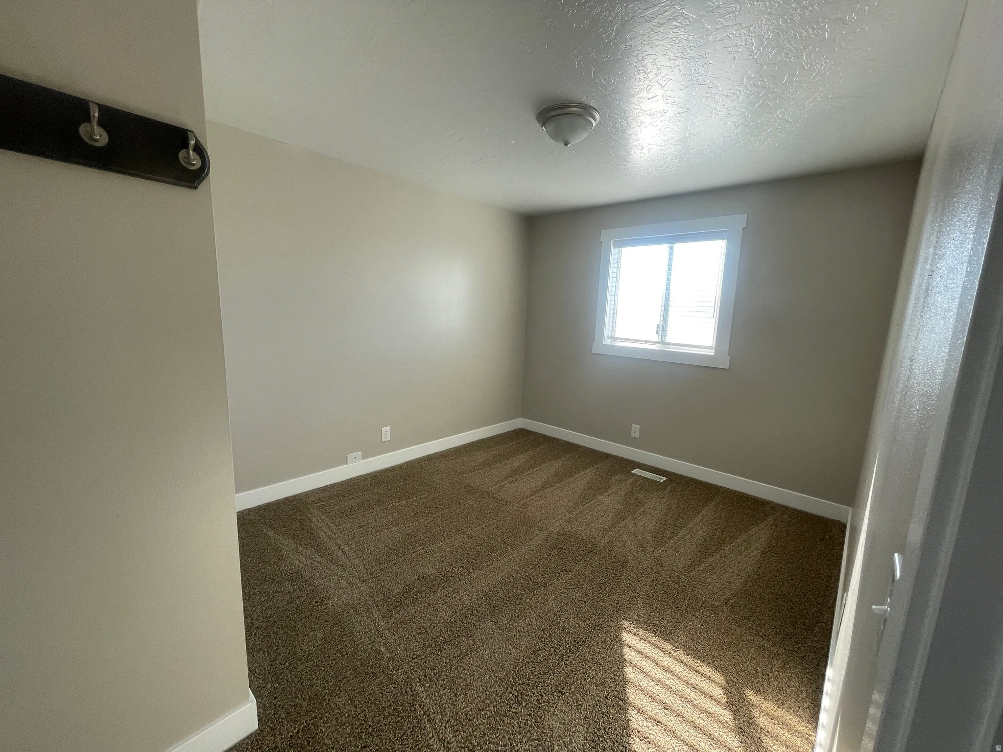 Spare room featuring dark colored carpet and a textured ceiling