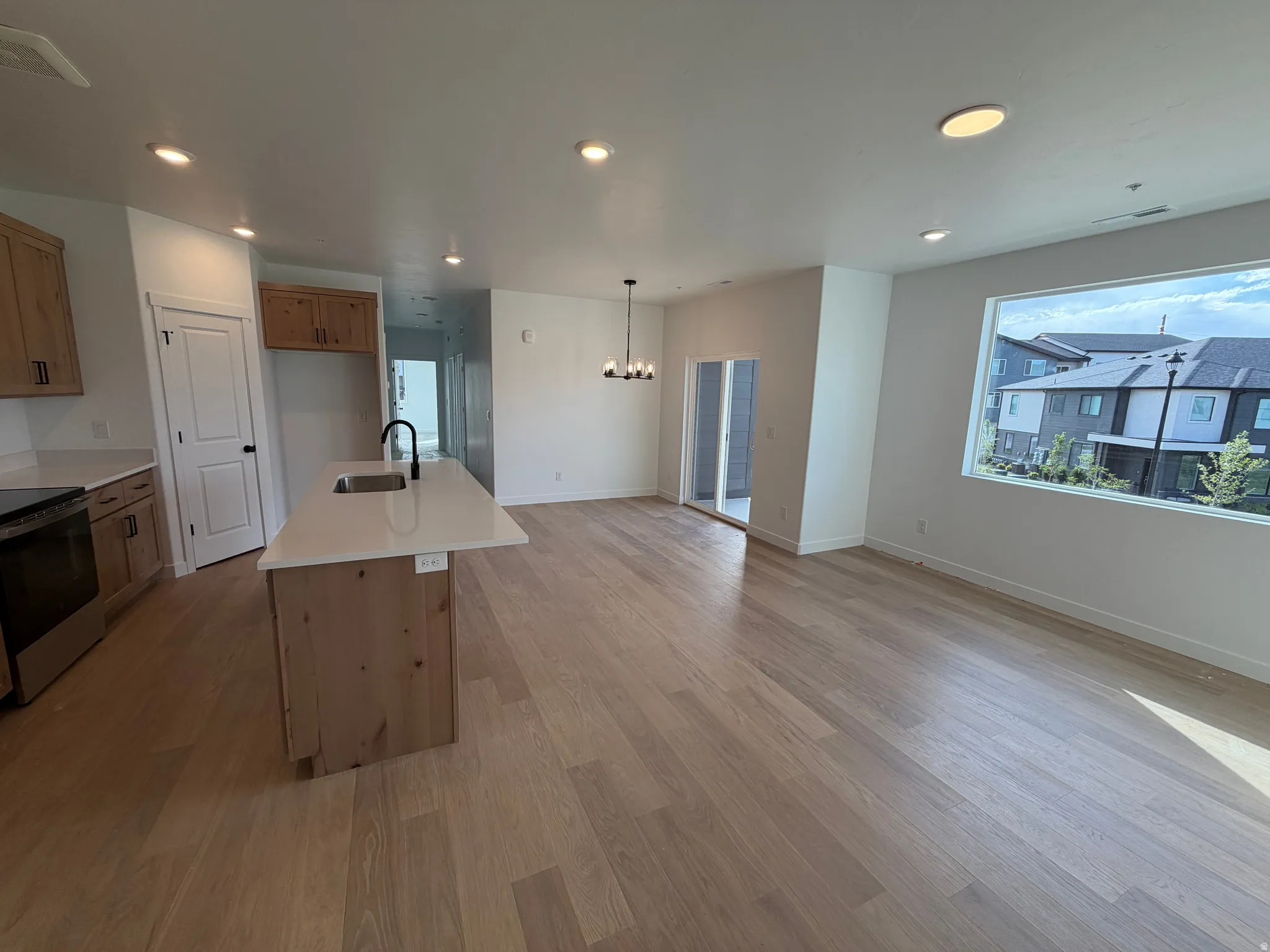 Open-concept living space featuring wood-finish flooring, recessed lighting, and a kitchen island with a built-in sink and countertop seating