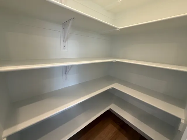 Walk-in pantry with extensive wraparound shelving and wood-finish flooring