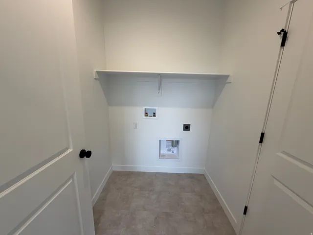Dedicated laundry area featuring a built-in shelf, plumbing hookups, electrical outlet, and neutral-toned flooring
