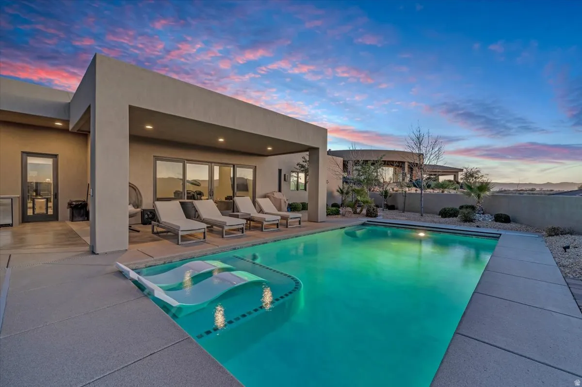 Pool at dusk with a patio and a fenced backyard