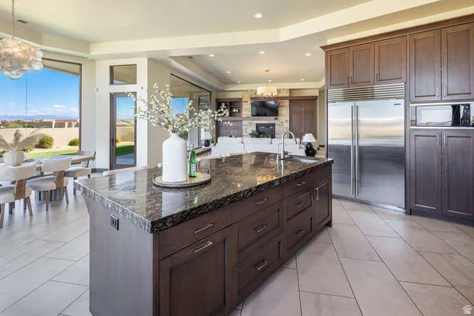 Kitchen with decorative light fixtures, dark brown cabinetry, a chandelier, stainless steel built in fridge, and recessed lighting