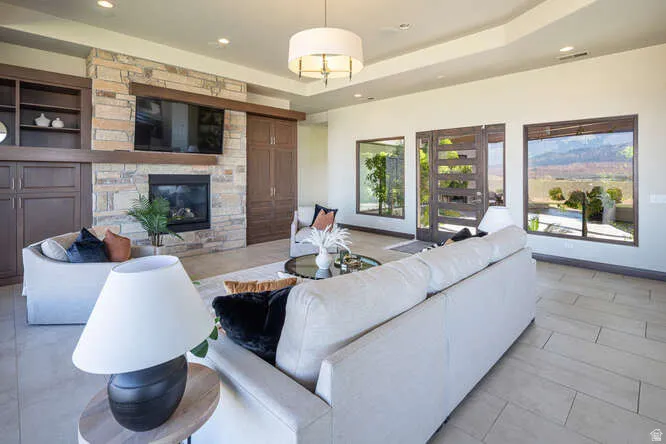Living area featuring a raised ceiling, recessed lighting, and a fireplace