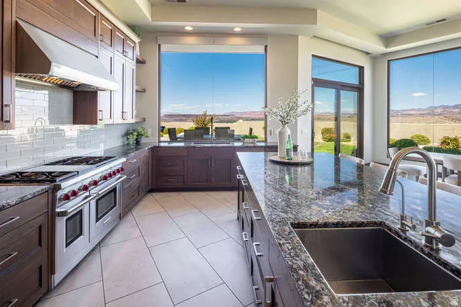 Kitchen with range with two ovens, dark stone counters, light tile patterned floors, tasteful backsplash, and range hood