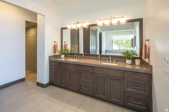 Bathroom with double vanity, light tile patterned floors, and a shower stall