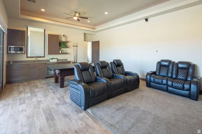 Living room featuring a raised ceiling, ceiling fan, recessed lighting, and light wood-style floors