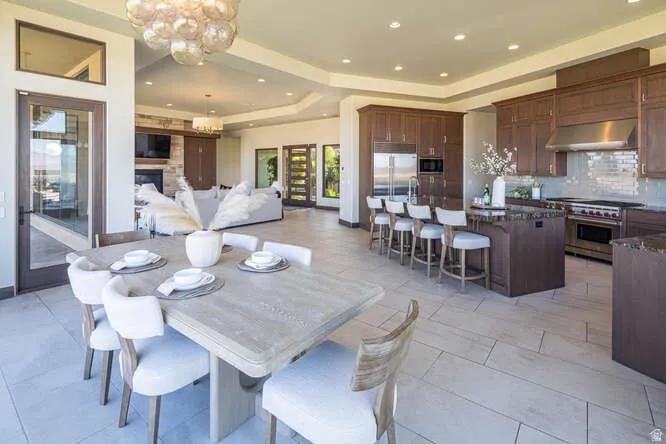 Dining room with a tray ceiling, a chandelier, recessed lighting, a fireplace, and light tile patterned floors