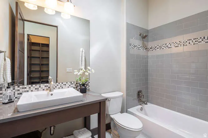 Full bath with washtub / shower combination, tasteful backsplash, and vanity