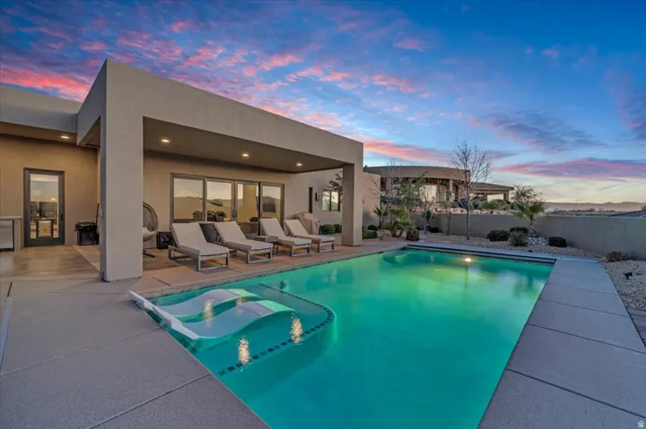 Pool at dusk with a patio and a fenced backyard