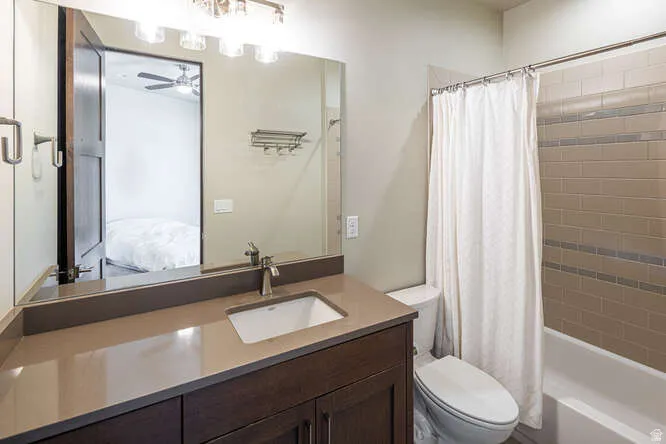 Full bathroom with shower / tub combo with curtain, vanity, ensuite bath, and a ceiling fan