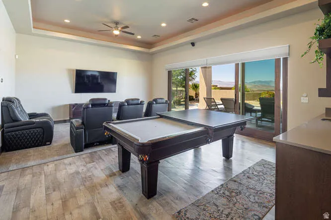 Playroom with light wood finished floors, a raised ceiling, pool table, and recessed lighting