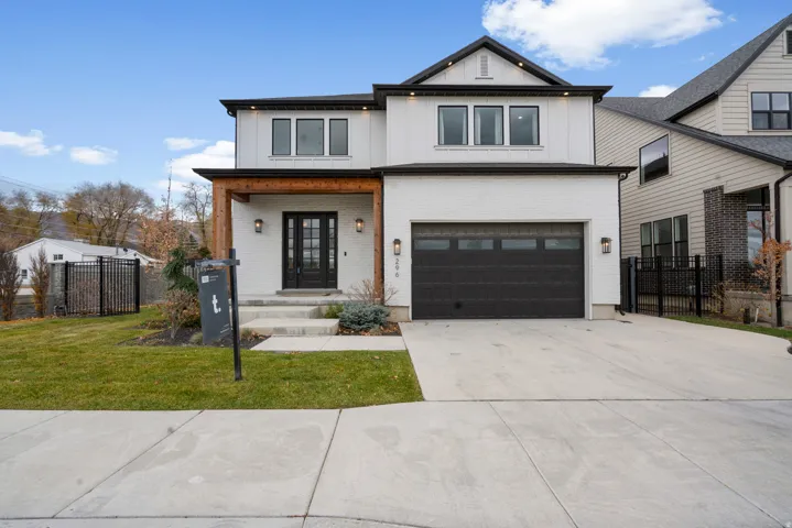 Modern farmhouse featuring a porch, driveway, a garage, brick siding, and board and batten siding
