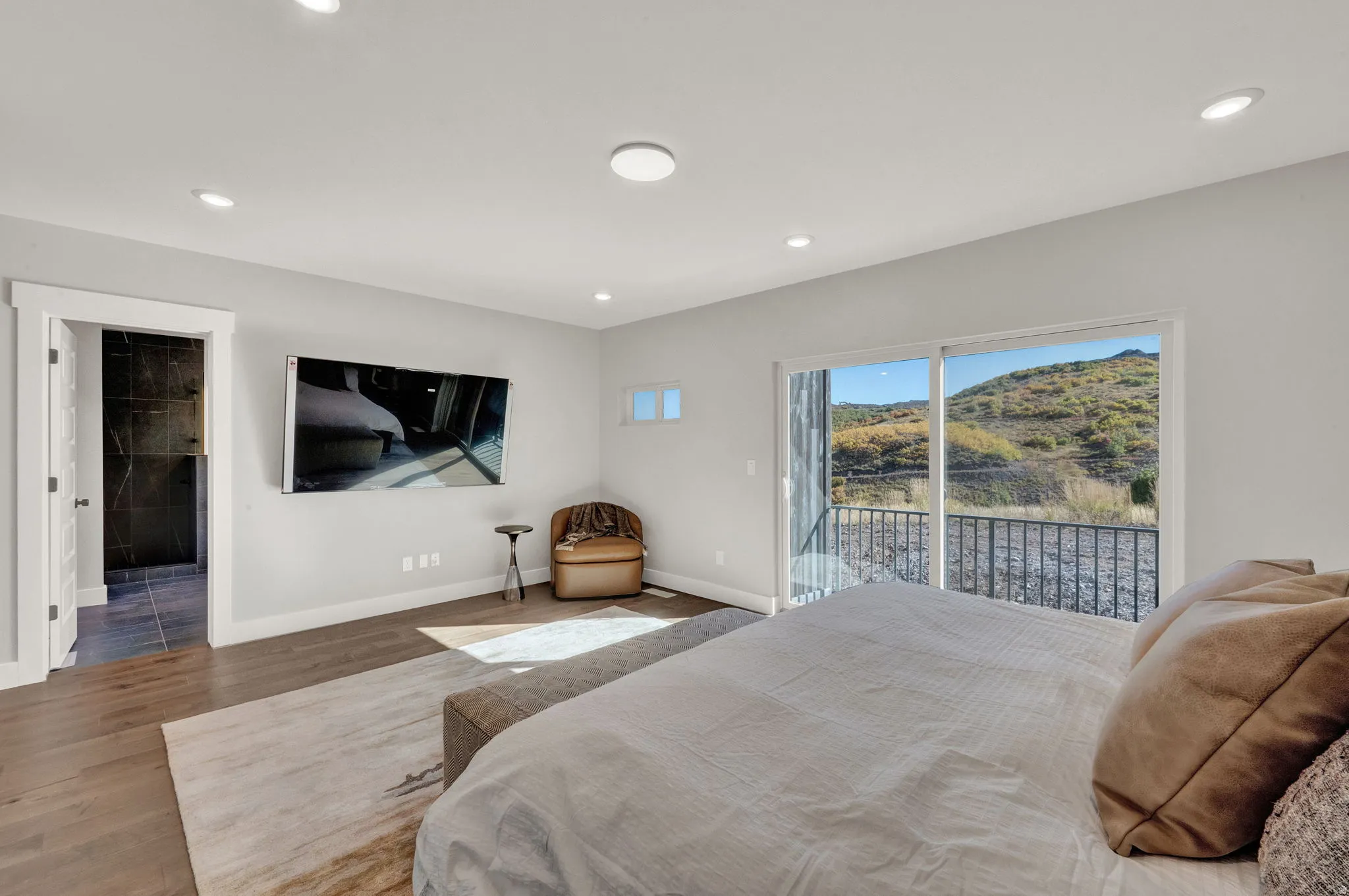 Bedroom with wood finished floors, recessed lighting, access to outside, and connected bathroom