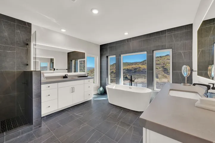 Bathroom with tile walls, a freestanding tub, two vanities, a shower stall, and recessed lighting