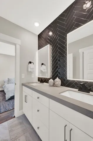 Ensuite bathroom featuring double vanity and backsplash