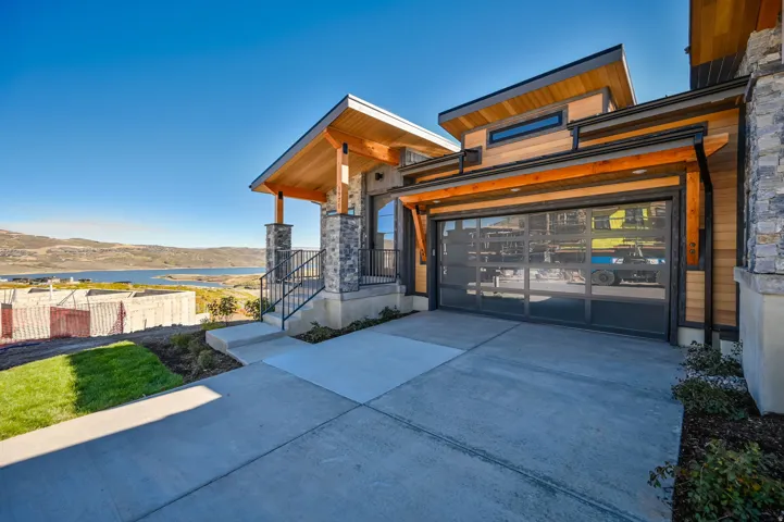 View of home's exterior with driveway, a water view, a garage, and stone siding