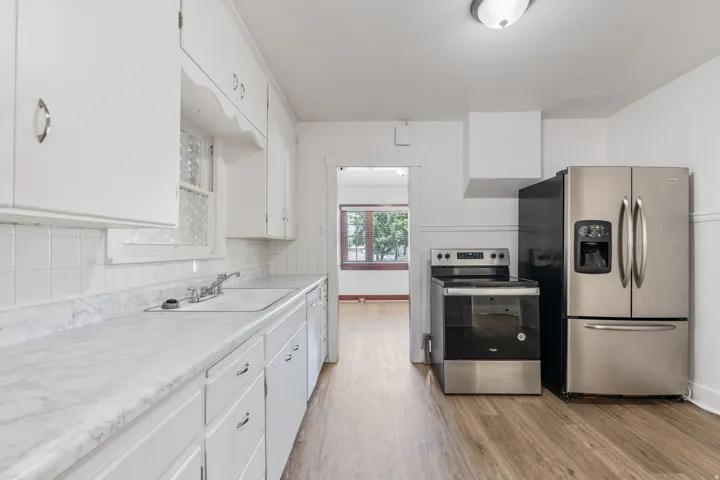 Kitchen with appliances with stainless steel finishes, white cabinets, light countertops, light wood-style floors, and decorative backsplash