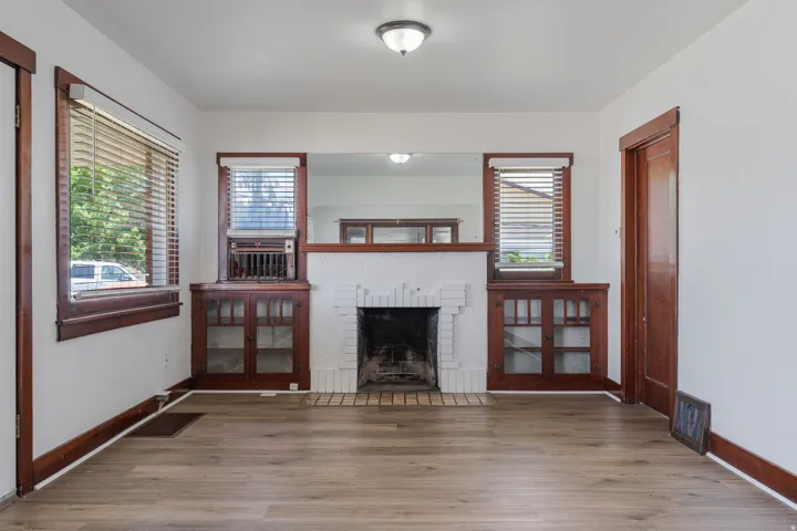 Unfurnished living room featuring wood finished floors and a brick fireplace