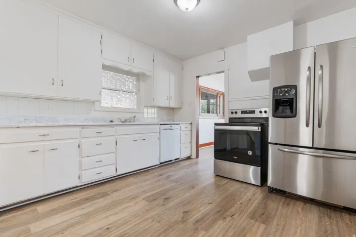 Kitchen with appliances with stainless steel finishes, light countertops, light wood-style flooring, and white cabinetry