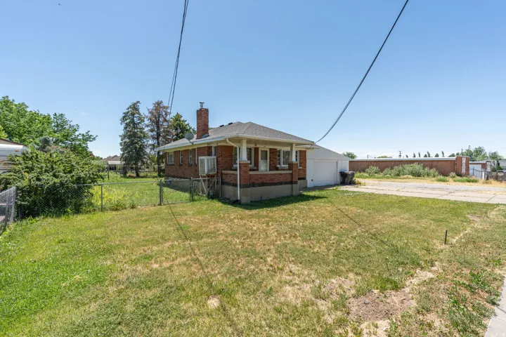 Back of property featuring brick siding, concrete driveway, a chimney, and an attached garage