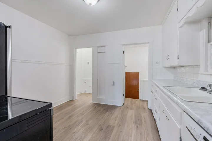 Kitchen featuring white cabinetry, light countertops, light wood finished floors, dishwasher, and tasteful backsplash
