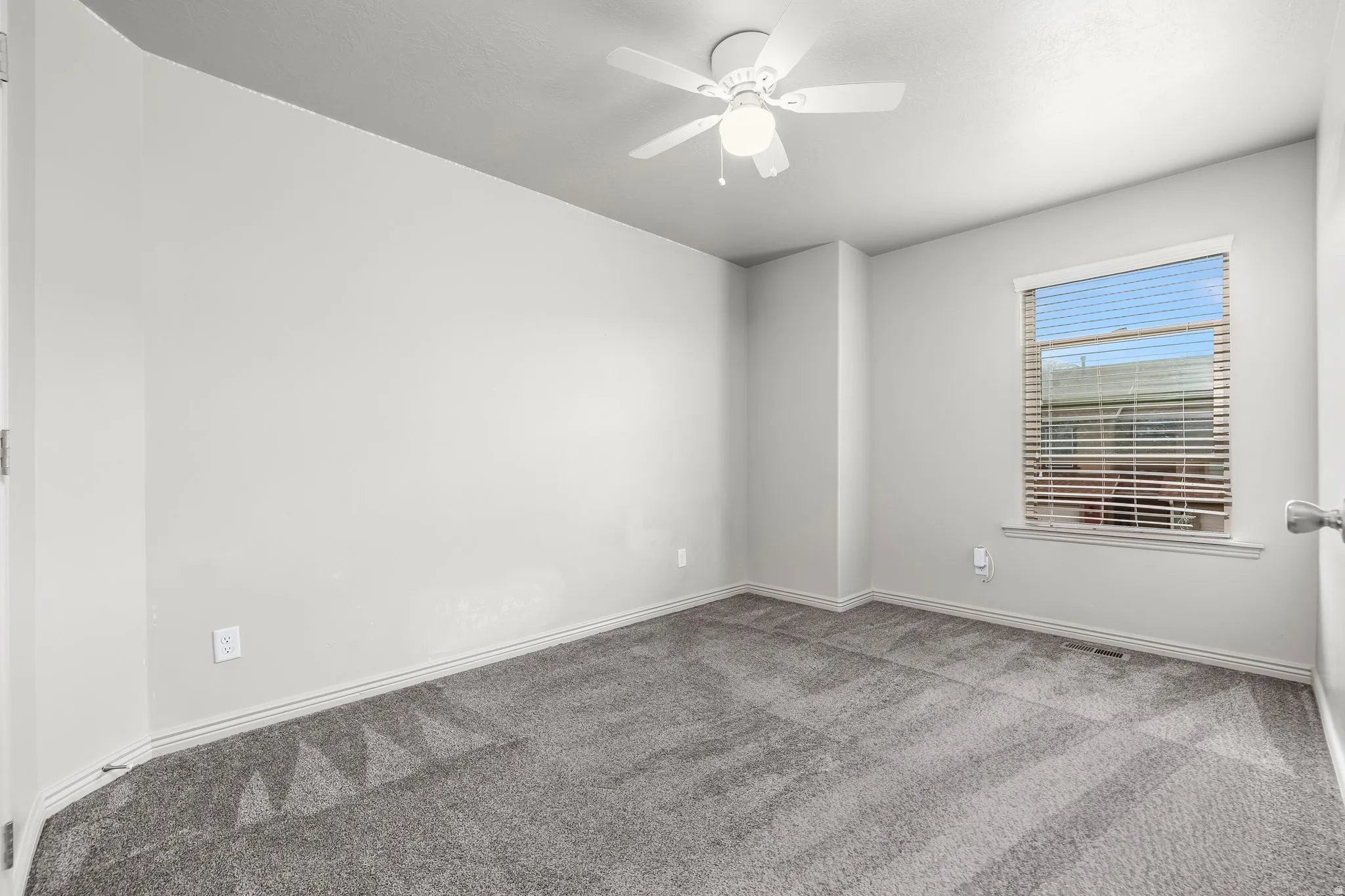 Carpeted spare room with baseboards and ceiling fan