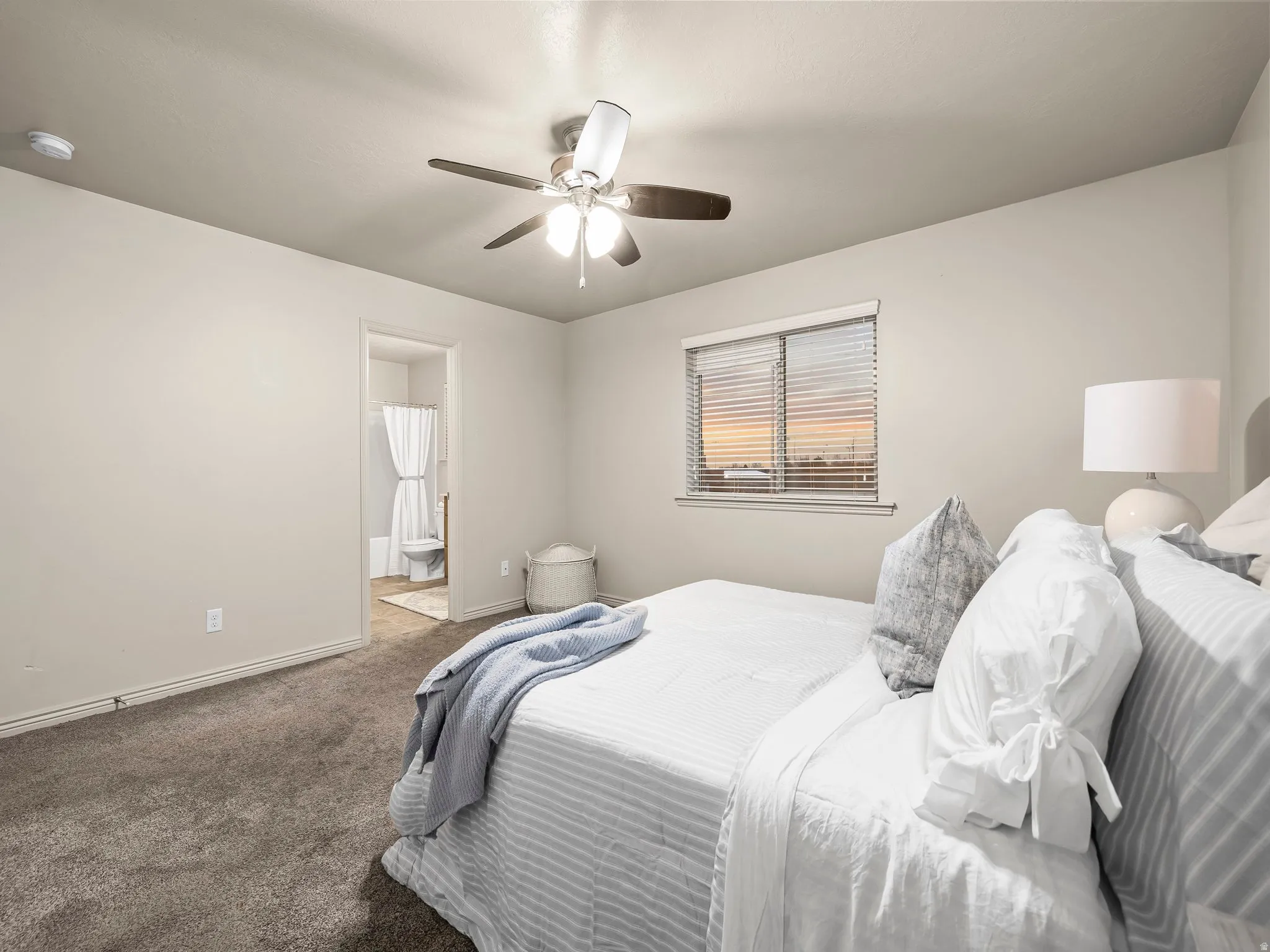 Bedroom with carpet, a ceiling fan, and ensuite bathroom